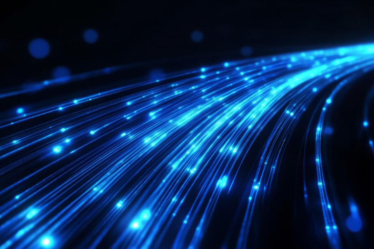 Fibra óptica com feixes de luz azul representando transmissão de dados em alta velocidade.