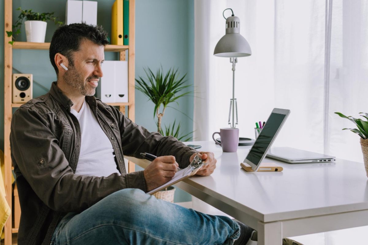 Homem trabalhando em home office em Petrópolis com notebook, tablet e internet estável em ambiente residencial